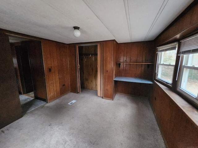 unfurnished bedroom featuring wooden walls and a closet