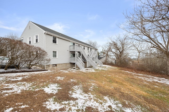 snow covered back of property featuring a balcony