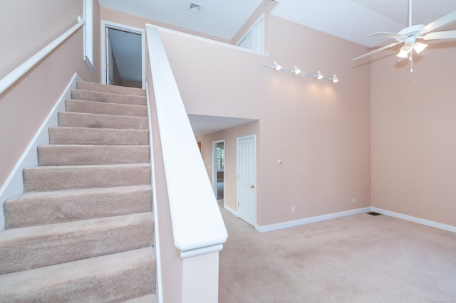 stairs with carpet, ceiling fan, and vaulted ceiling