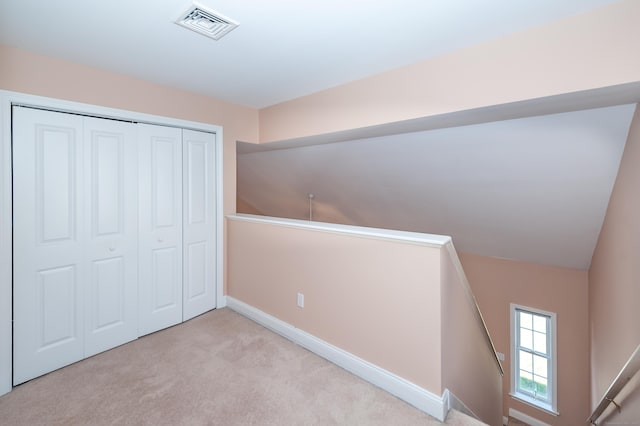 unfurnished bedroom featuring light carpet and a closet