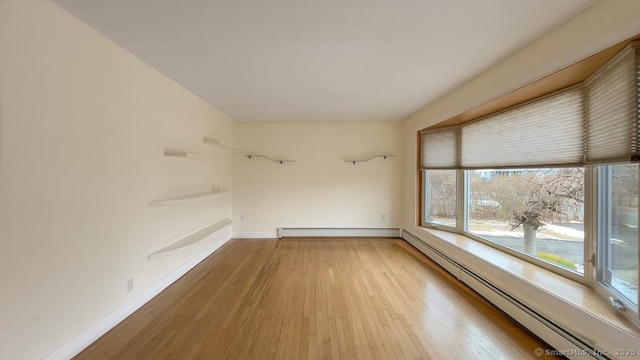 empty room with hardwood / wood-style flooring and a baseboard radiator