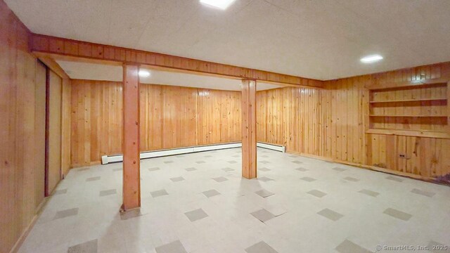 basement featuring baseboard heating and wood walls