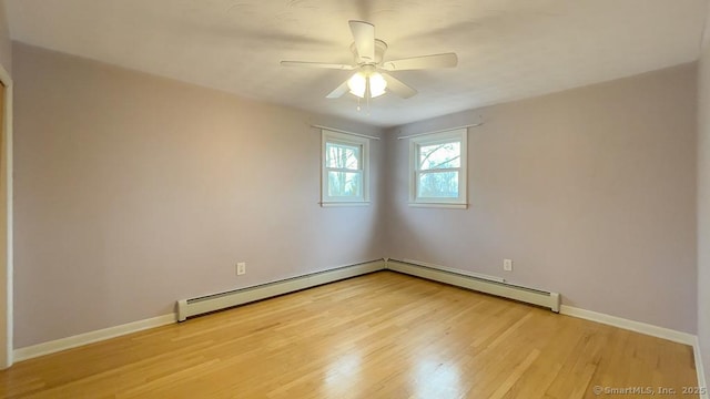 spare room with ceiling fan, baseboard heating, and light hardwood / wood-style floors