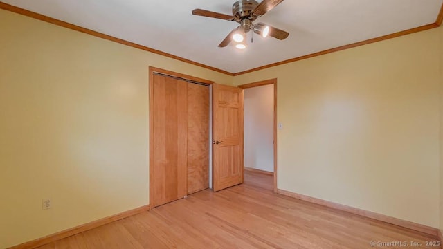 unfurnished bedroom with ceiling fan, a closet, light wood-type flooring, and ornamental molding