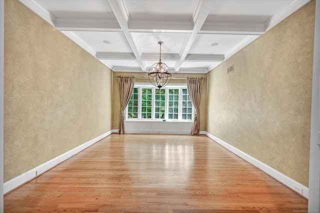 unfurnished dining area featuring coffered ceiling, crown molding, wood-type flooring, a notable chandelier, and beamed ceiling