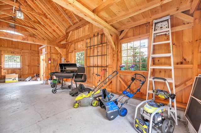 miscellaneous room featuring beam ceiling, wood walls, high vaulted ceiling, and concrete flooring