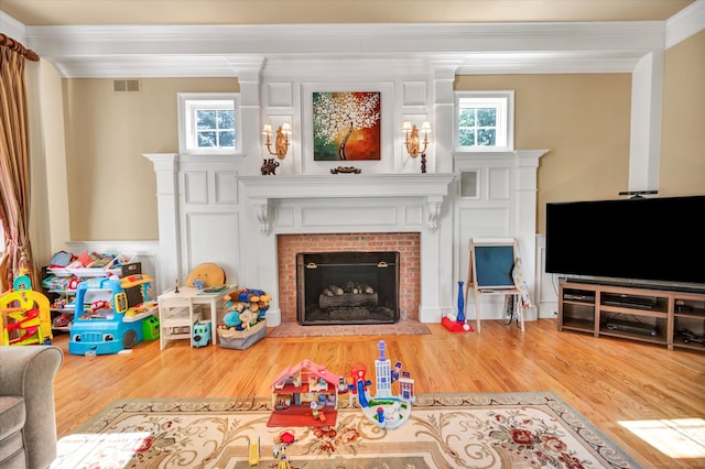 living room with a fireplace, a healthy amount of sunlight, hardwood / wood-style flooring, and crown molding