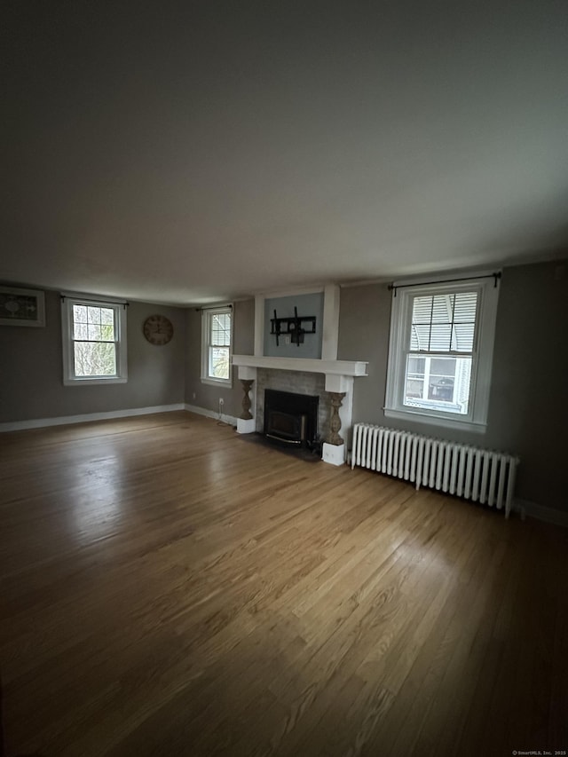 unfurnished living room with radiator and wood-type flooring