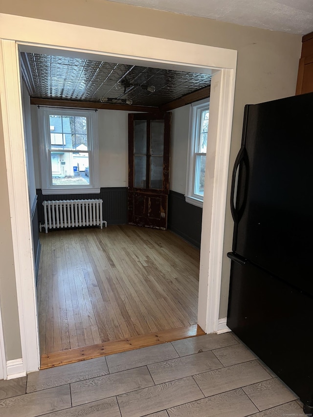 empty room featuring a healthy amount of sunlight, radiator heating unit, and light hardwood / wood-style floors