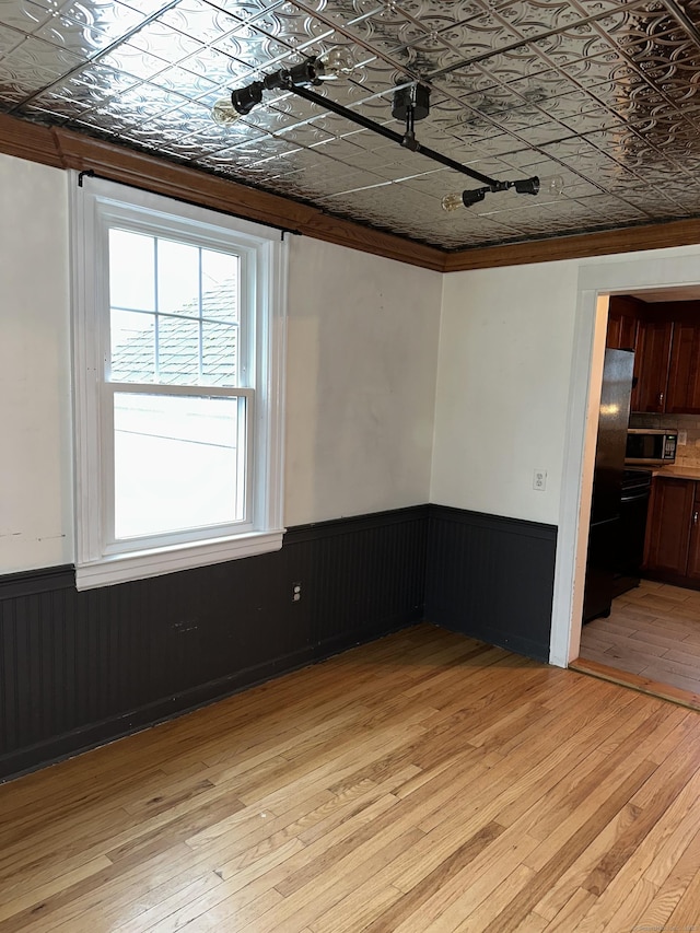 unfurnished room featuring ornamental molding and light hardwood / wood-style flooring