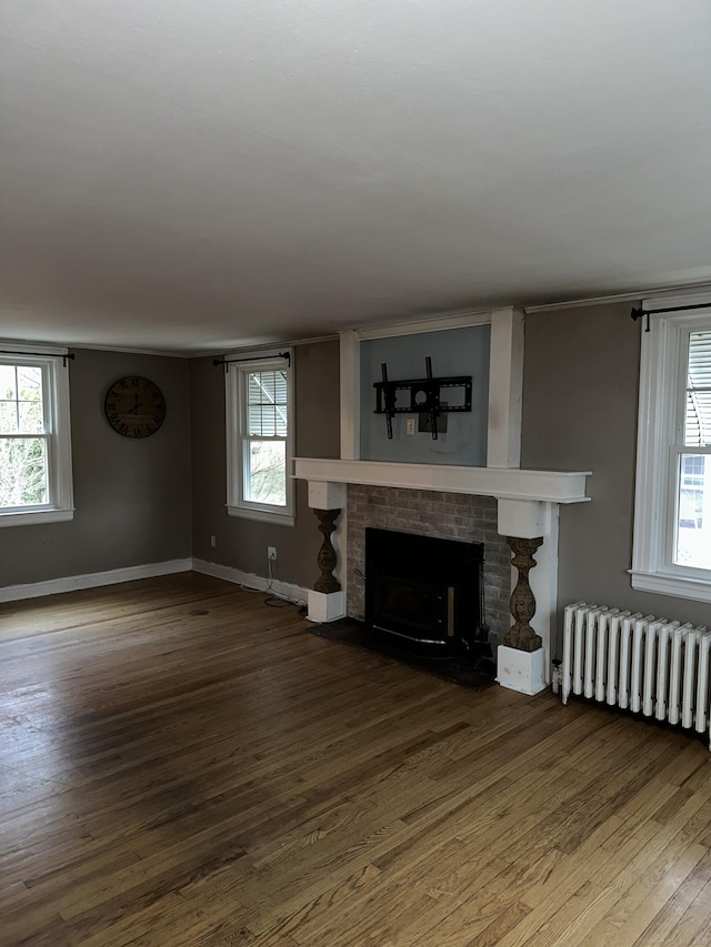 unfurnished living room with a brick fireplace, radiator, and hardwood / wood-style floors