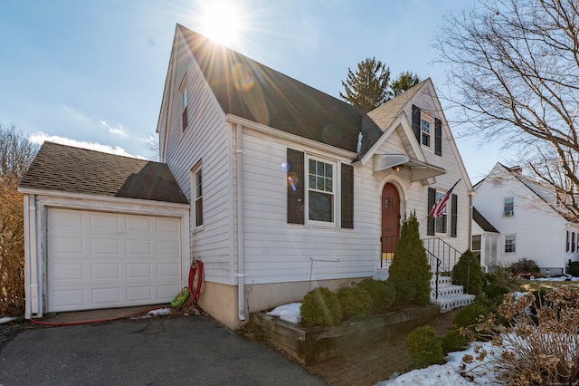 view of front of home featuring a garage, driveway, and a shingled roof