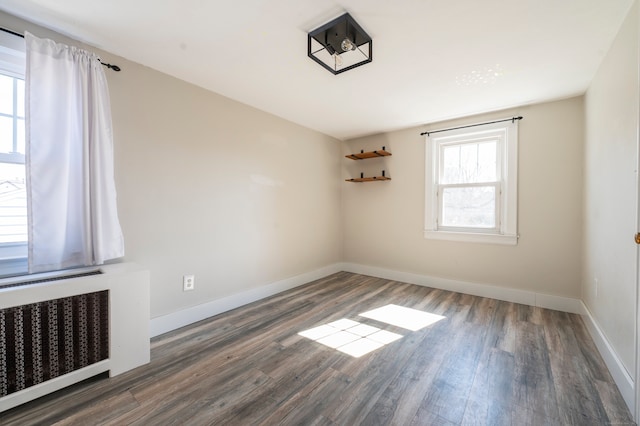 unfurnished room featuring radiator, dark wood-style flooring, and baseboards