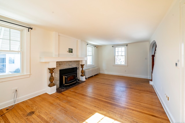 unfurnished living room featuring radiator, light wood-style floors, and baseboards