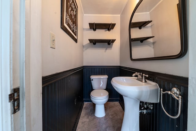 half bath with a wainscoted wall and toilet