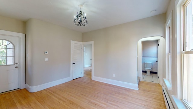 interior space featuring light wood-type flooring, a baseboard radiator, and an inviting chandelier