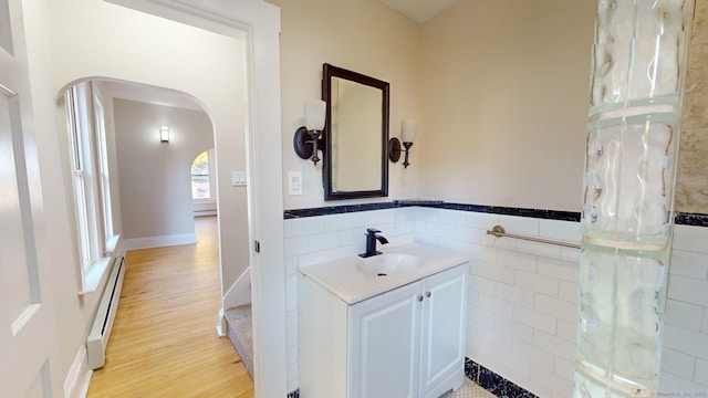 bathroom with hardwood / wood-style flooring, vanity, baseboard heating, and tile walls