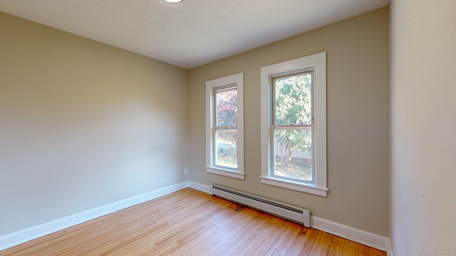 empty room with light wood-type flooring and a baseboard radiator