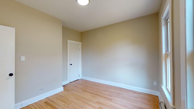 empty room featuring baseboard heating and light wood-type flooring