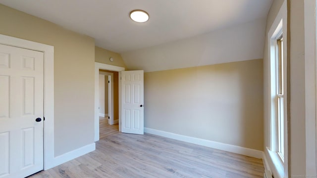 unfurnished bedroom featuring multiple windows, light hardwood / wood-style floors, a closet, and lofted ceiling