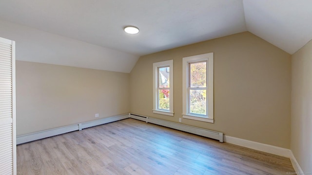 additional living space featuring light hardwood / wood-style flooring, vaulted ceiling, and baseboard heating