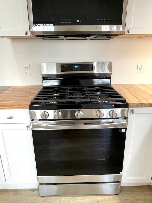 kitchen featuring wood counters, light hardwood / wood-style floors, white cabinetry, and stainless steel appliances