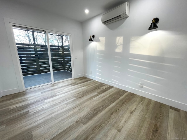 empty room with light hardwood / wood-style floors and a wall unit AC