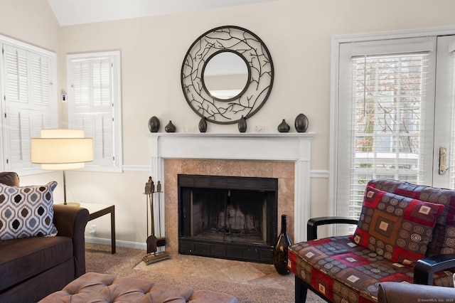 living room featuring a healthy amount of sunlight, vaulted ceiling, and a tiled fireplace