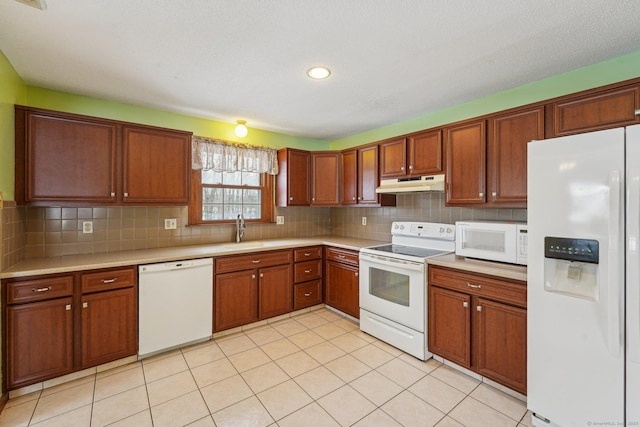 kitchen featuring tasteful backsplash, light countertops, a sink, white appliances, and under cabinet range hood