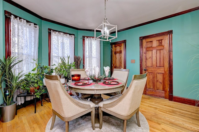 dining space with an inviting chandelier, light hardwood / wood-style floors, and ornamental molding