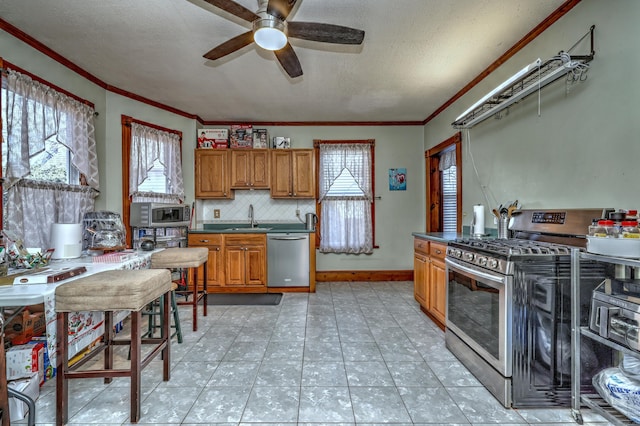 kitchen featuring backsplash, sink, ceiling fan, a textured ceiling, and appliances with stainless steel finishes