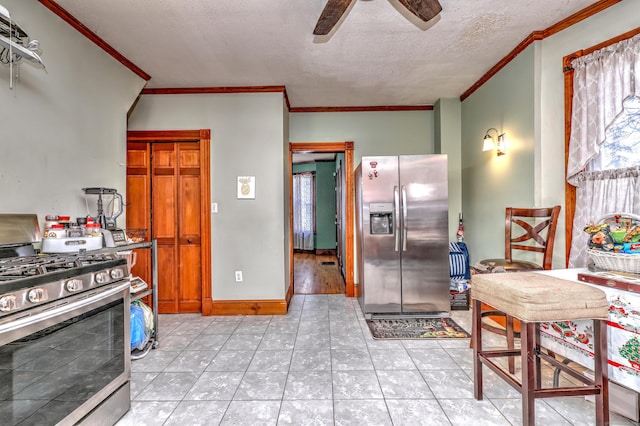 kitchen with ceiling fan, stainless steel appliances, crown molding, a textured ceiling, and light tile patterned flooring