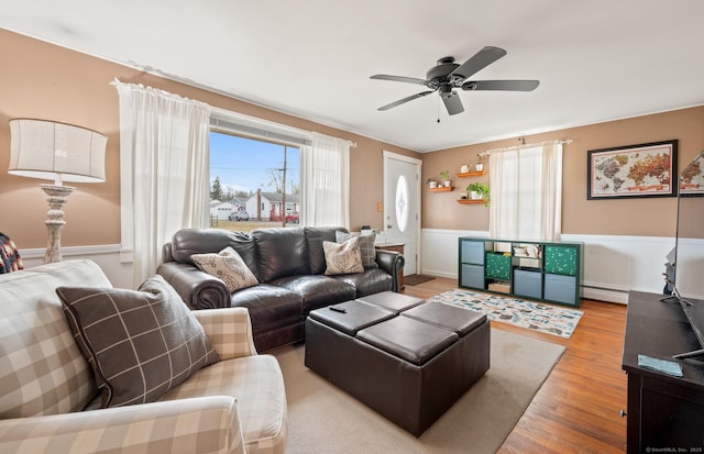 living room with baseboard heating, ceiling fan, and wood-type flooring