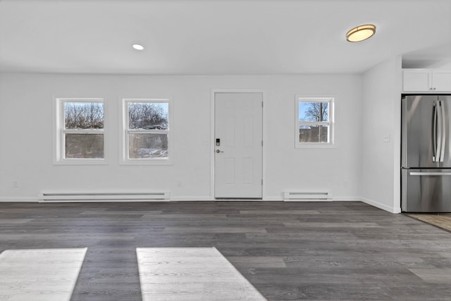 interior space featuring baseboard heating, dark wood-type flooring, and a healthy amount of sunlight