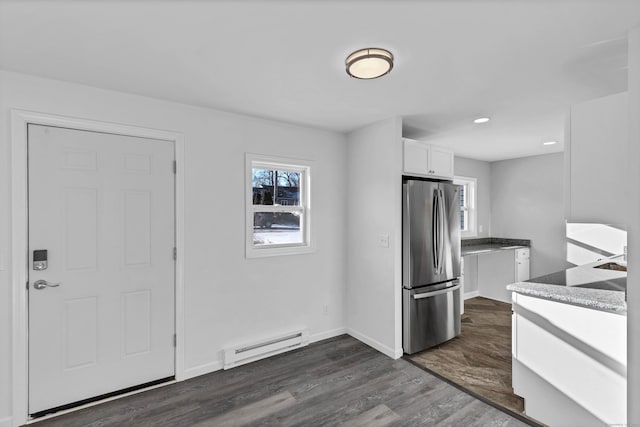 kitchen with white cabinets, dark hardwood / wood-style floors, stainless steel fridge, light stone countertops, and a baseboard radiator