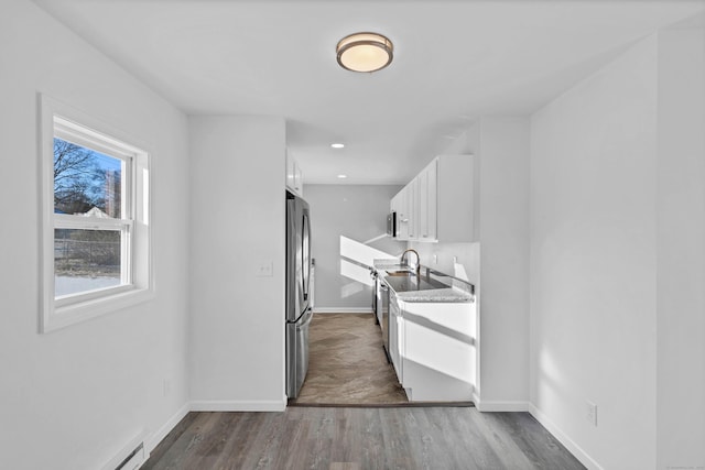 kitchen featuring dark hardwood / wood-style floors, stainless steel fridge, white cabinetry, and baseboard heating