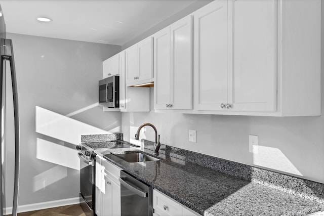 kitchen featuring white cabinets, stainless steel appliances, dark stone counters, and sink