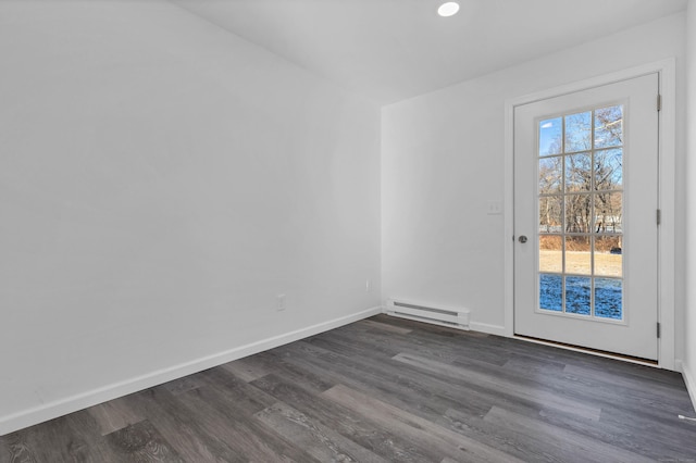 unfurnished room featuring dark wood-type flooring and a baseboard heating unit