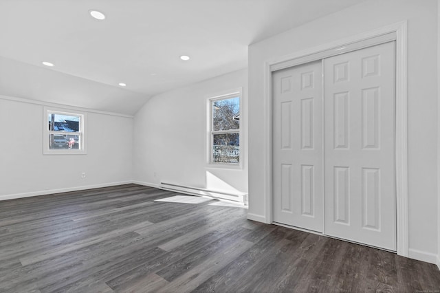 unfurnished bedroom with dark hardwood / wood-style flooring, a closet, vaulted ceiling, and baseboard heating