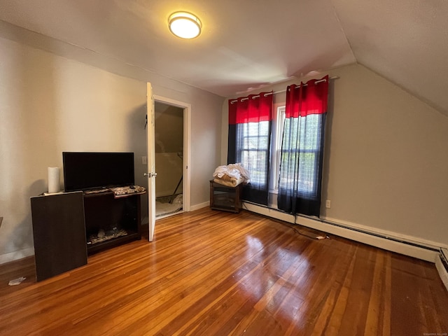 additional living space featuring baseboard heating, lofted ceiling, and hardwood / wood-style flooring