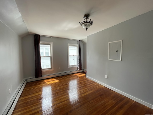 spare room with electric panel, lofted ceiling, dark hardwood / wood-style floors, and a baseboard heating unit