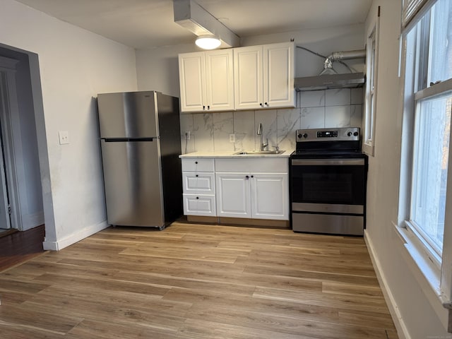 kitchen with tasteful backsplash, stainless steel appliances, sink, white cabinets, and light hardwood / wood-style floors