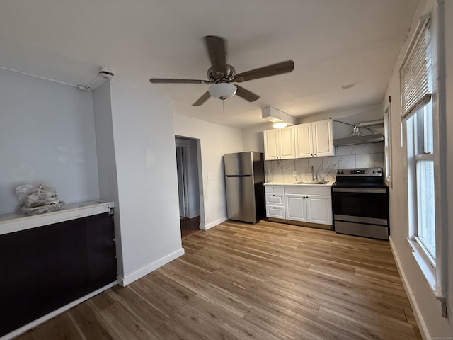 kitchen featuring sink, stainless steel appliances, light hardwood / wood-style floors, decorative backsplash, and white cabinets