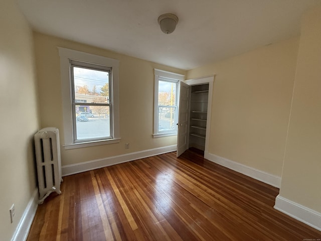 unfurnished bedroom with radiator heating unit and dark wood-type flooring