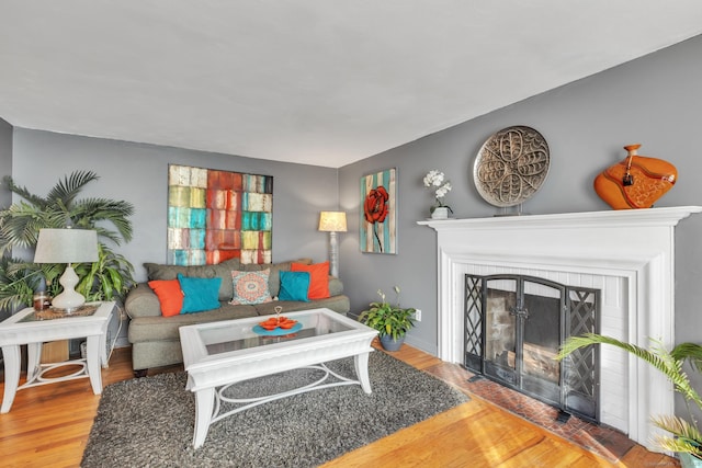 living room featuring hardwood / wood-style flooring and a brick fireplace