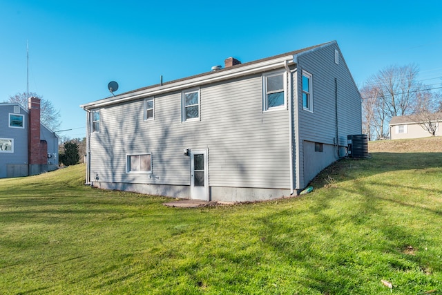 rear view of house featuring central air condition unit and a yard