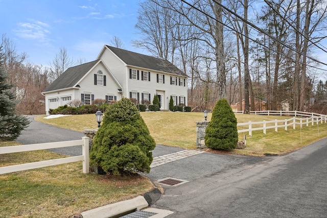 colonial inspired home with a garage, a fenced front yard, and a front yard