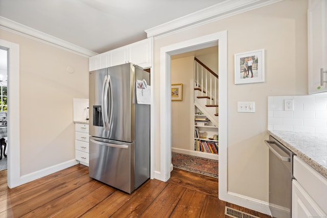 kitchen with backsplash, crown molding, light stone countertops, white cabinetry, and stainless steel appliances