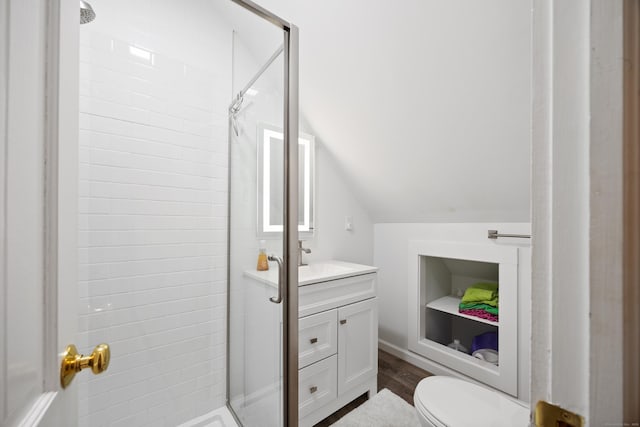 bathroom featuring vanity, vaulted ceiling, tiled shower, hardwood / wood-style floors, and toilet