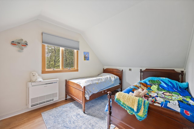 bedroom with light hardwood / wood-style floors, lofted ceiling, and heating unit